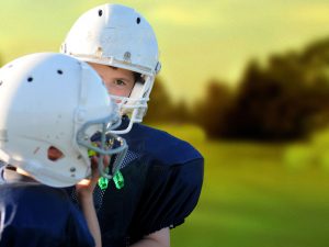 kids-wearing-footballs-helmets-and-gear-on-field