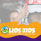 Volunteer placing a bicycle helmet on a child during the Lids for Kids bike helmet giveaway and bike safety event.